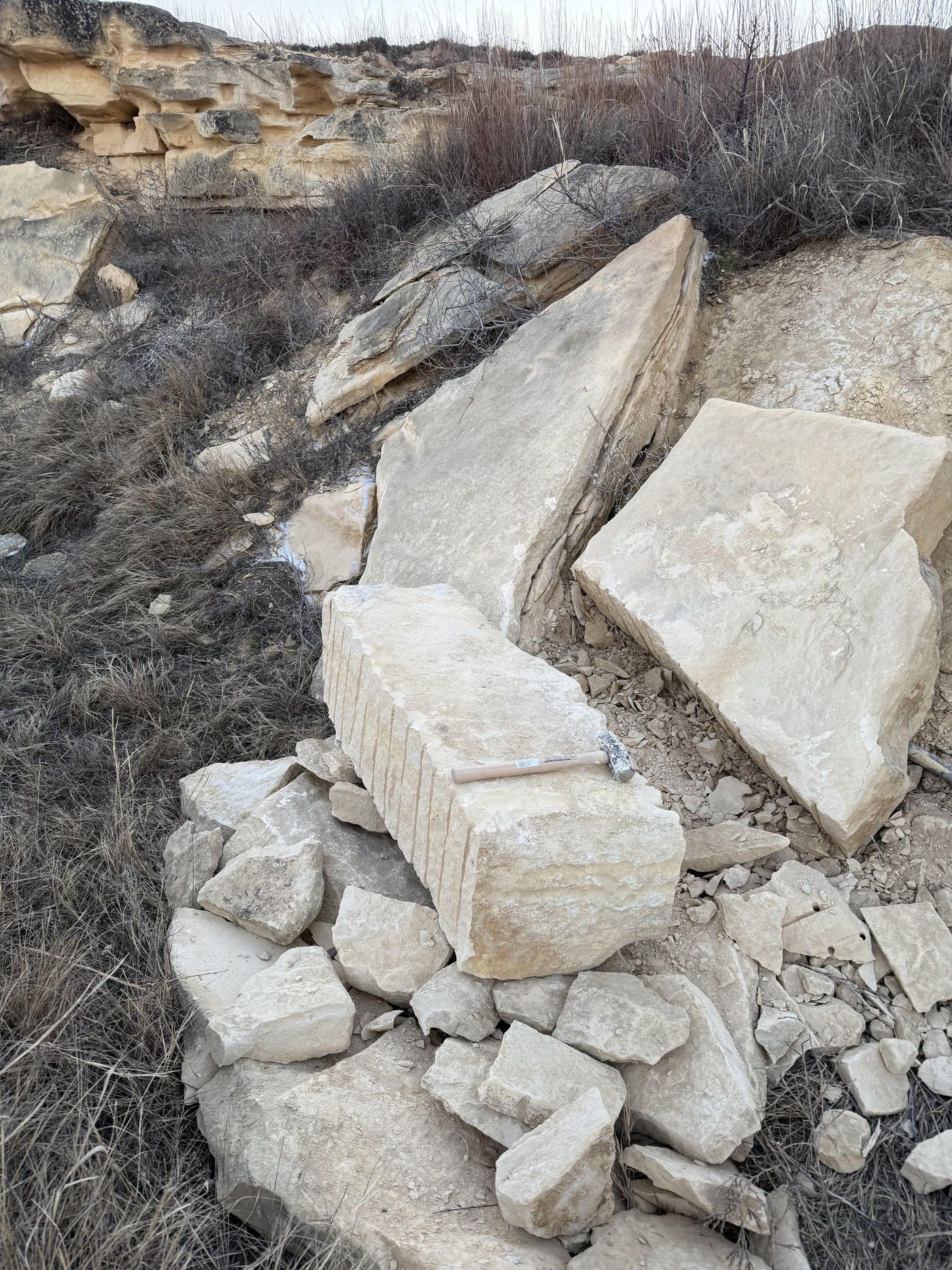 Hand-quarried limestone blocks at a Colorado quarry site, with stone-mason tools nearby